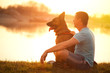 Relaxed man and dog enjoying summer sunset or sunrise
