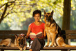 Woman is sitting on a bench with two german shepherds